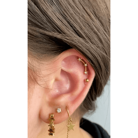 Een vrouw draagt een paar gouden sterren en ketting oorbellen