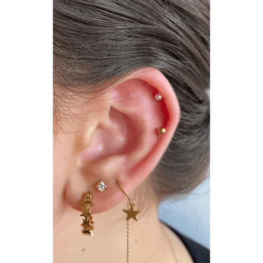 Een vrouw met een gouden ster als oorpiercing