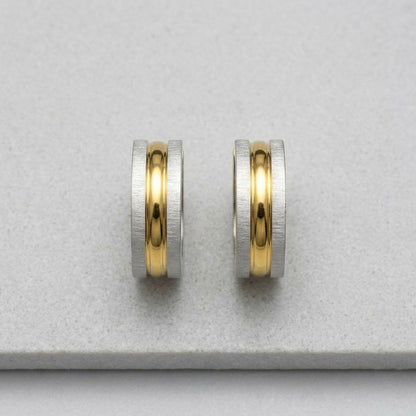 Aramat Jewels bicolor matte stainless steel hoop earrings with a brushed silver outer band and a polished gold inner band, 20x7mm.