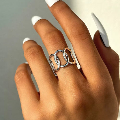 Aramat Jewels brede zilverkleurige RVS ring met open ovale schakels, gedragen om een vinger met witte nagels.