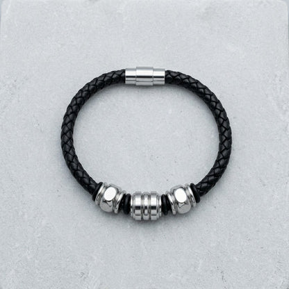 Aramat Jewels gevlochten zwarte leren herenarmband met drie zilverkleurige edelstalen kralen en magnetische sluiting.