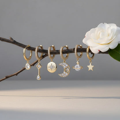 Aramat Jewels gold plated hoop earrings set with celestial charms: moon, star, planet, and starburst. Clear cubic zirconia accents.
