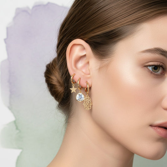 Aramat Jewels gold plated hoop earring set with charms: star, clear gem, Hamsa hand, evil eye, ball, and evil eye with blue stone.