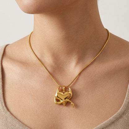 Aramat Jewels gold stainless steel heart pendant with devil motif on a snake chain necklace worn by a model.