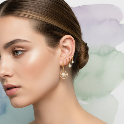 Aramat Jewels set of 3 pairs of gold-plated 925 silver hoop earrings with star and compass designs, accented with cubic zirconia.