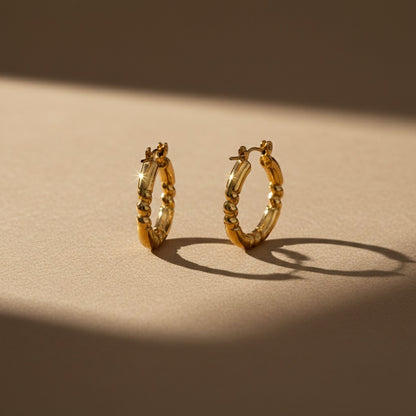 Aramat Jewels gold-coloured stainless steel hoop earrings with a striped engraving, 26x25mm, featuring a hinge closure.