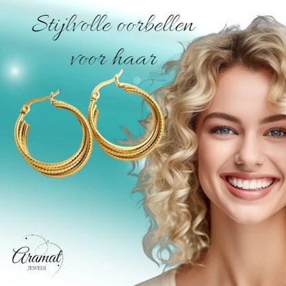 Aramat Jewels gold triple hoop earrings with striped texture, 25mm diameter, worn by a smiling blonde model.