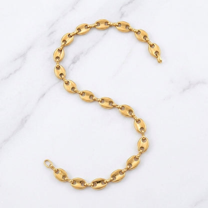 Aramat Jewels goudkleurige stalen koffieboon ketting van 60 cm met 5,2 mm schakels op een marmeren achtergrond.
