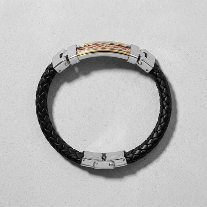 Aramat Jewels stoere zwarte gevlochten PU leren armband met RVS accenten in goud en rosé op een grijze achtergrond.
