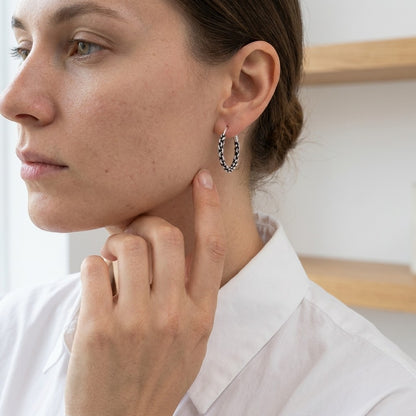 Aramat Jewels 16mm silver Bali hoop earrings with an ethnic braided design, worn by a woman.