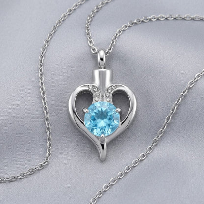 Aramat Jewels silver-tone stainless steel heart-shaped cremation pendant with a blue zirconia and small clear stones.