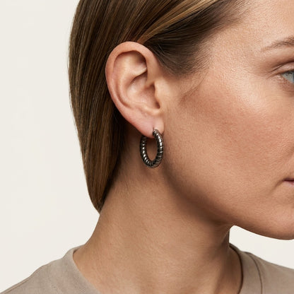 Aramat Jewels silver-coloured hollow steel hoop earrings with a ribbed stripe motif, 30mm diameter.