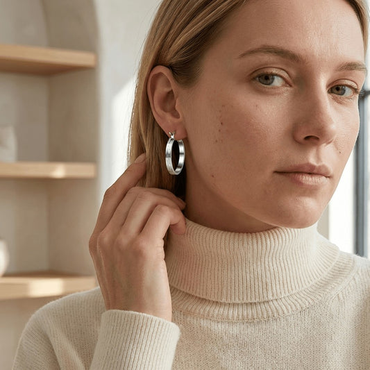 Aramat Jewels silver-tone stainless steel hoop earrings with a subtle striped pattern, 20mm diameter, worn by a woman.