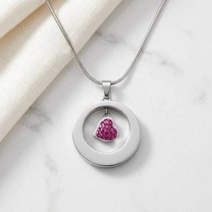 Aramat Jewels® zilverkleurige stalen ashanger rond met een hartje bezet met roze steentjes.