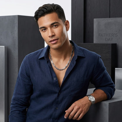 Man draagt een brede Aramat Jewels stalen koningsketting met kroonmotief en marine schakels bij een donkerblauw overhemd.
