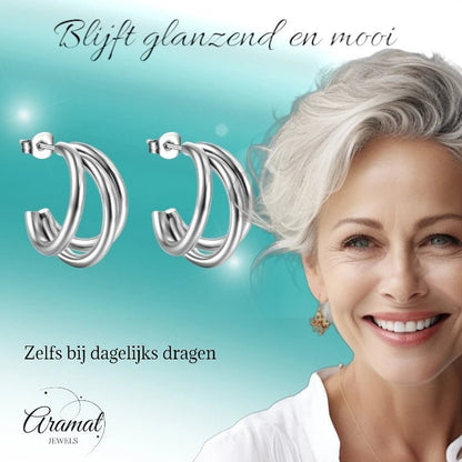 Aramat Jewels zilverkleurige triple halve oorringen van roestvrij staal, gedragen door een stralende vrouw.