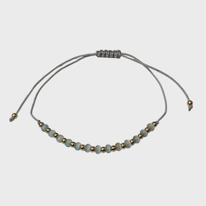 Aramat Jewels verstelbaar enkelbandje met grijze cats eye kralen en goudkleurige accenten op een grijs touwtje.