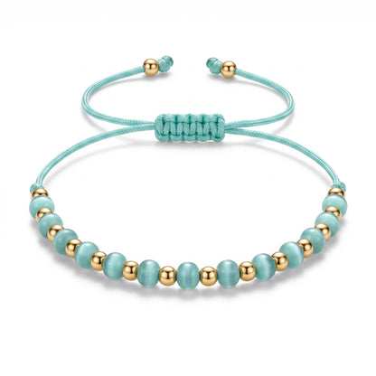 Aramat Jewels verstelbaar enkelbandje met lichtblauwe cats eye kralen en gouden accenten op een turquoise touwtje.