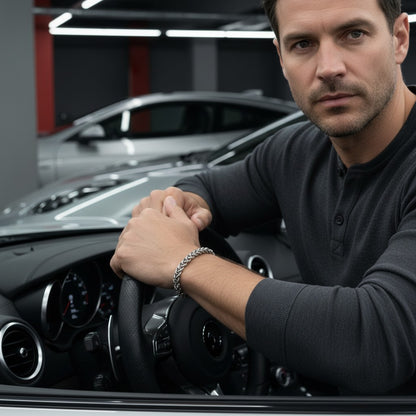 Man met een zilverkleurige Aramat Jewels vossenstaart armband van RVS, zittend achter het stuur van een auto.