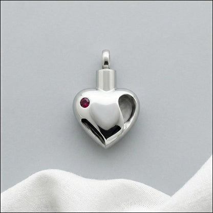 Aramat Jewels zilverkleurige stalen ashanger in hartvorm met rode zirkonia, waterbestendig.