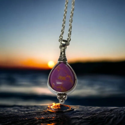 Een paarse stenen hanger hangt aan een zilveren ketting
