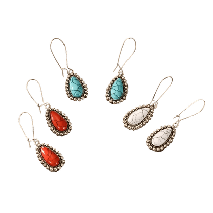 Drie paar druppelvormige oorbellen met edelstenen in turquoise, rode en witte kleuren, gezet in een sierlijk metalen montuur.