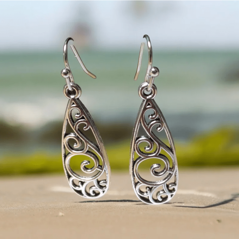 Paar zilveren druppelvormige oorbellen met ingewikkelde krulmotieven.