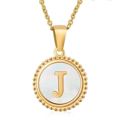 Hanger met vergulde ketting met de letter ’J’ op een parelmoeren achtergrond met kralenrand.