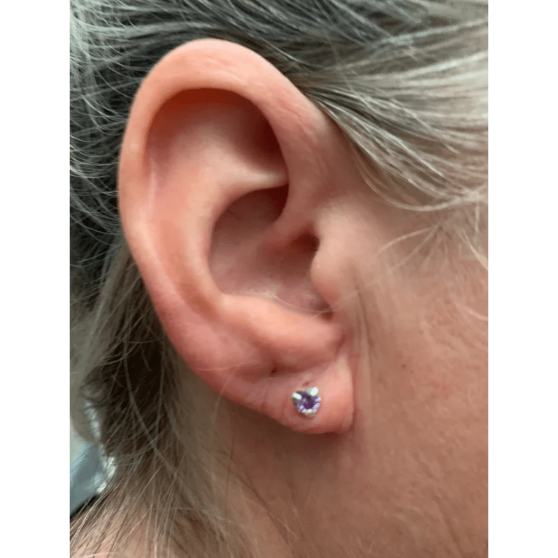 Een vrouwenoor met een enkele paarse steen