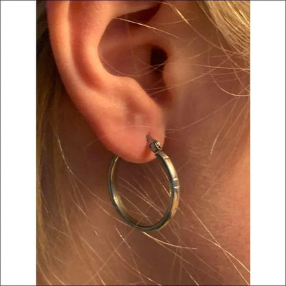 Een vrouw draagt een zilveren hoepel oorbel