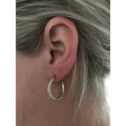 Een vrouw met grijs haar die een zilveren oorbel draagt