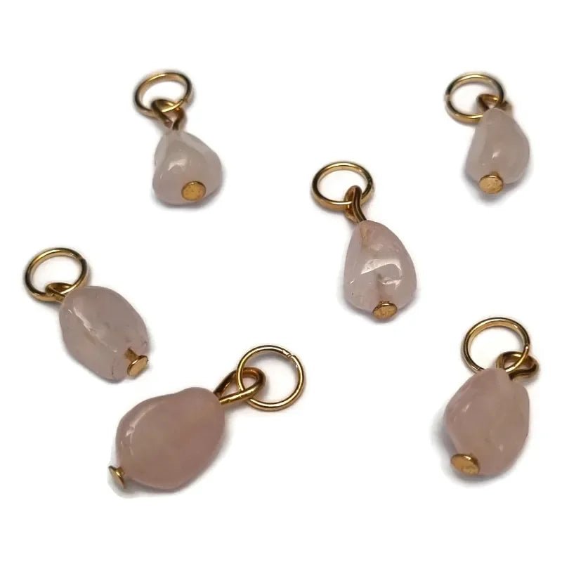 Een set van vier goudkleurige bedels met roze glaskralen