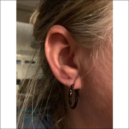 Een vrouw draagt een paar zwarte oorbellen