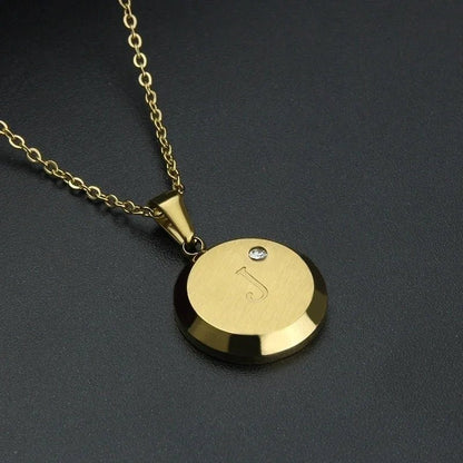 Goudkleurige ronde hanger met een ontwerp van muzieknoten en een klein kristallen accent aan een ketting.