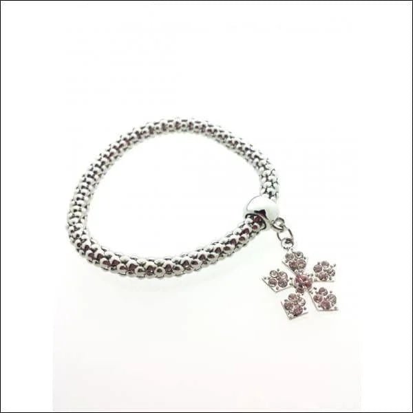 Een armband met een zilveren bedeltje en een roze kristallen bedeltje