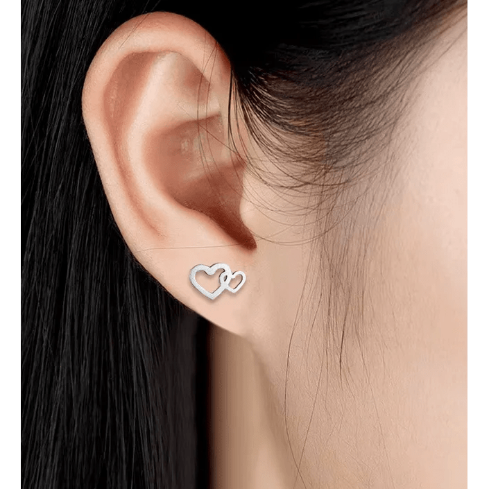 Zilveren dubbele hart oorbel gedragen op een oorlel.