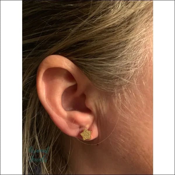 Het oor van een vrouw met een kleine gouden oorbel