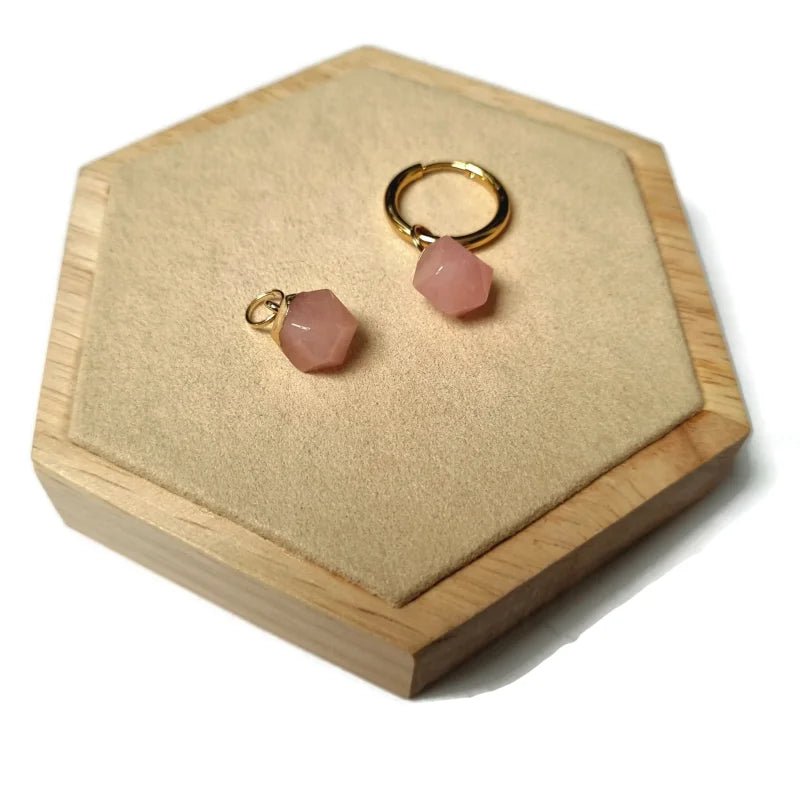 Een paar oorbellen van roze steen in een houten doosje