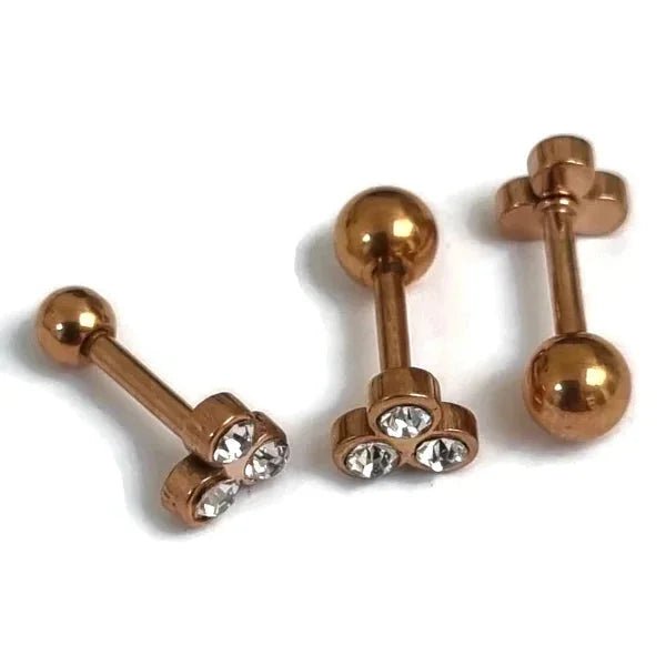 Drie paar goudkleurige chirurgische piercings met heldere kristallen