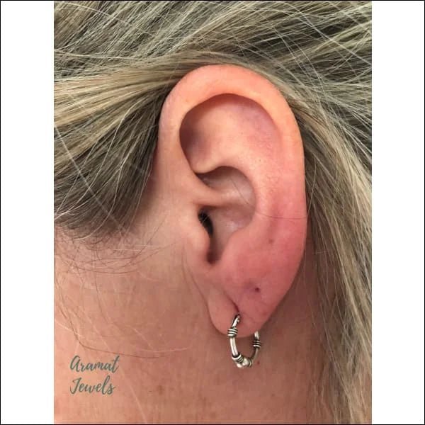 Het oor van een vrouw met een kleine oorpiercing